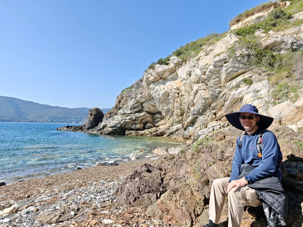 Stefan sitzt auf einem Stein an der kleinen Bucht.